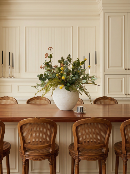 Dining room with a wooden table, floral arrangement, and wicker chairs.