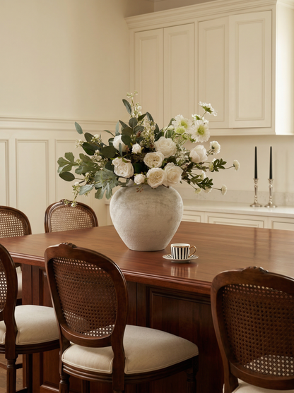 Dining room with wooden table, chairs, and a vase of flowers.