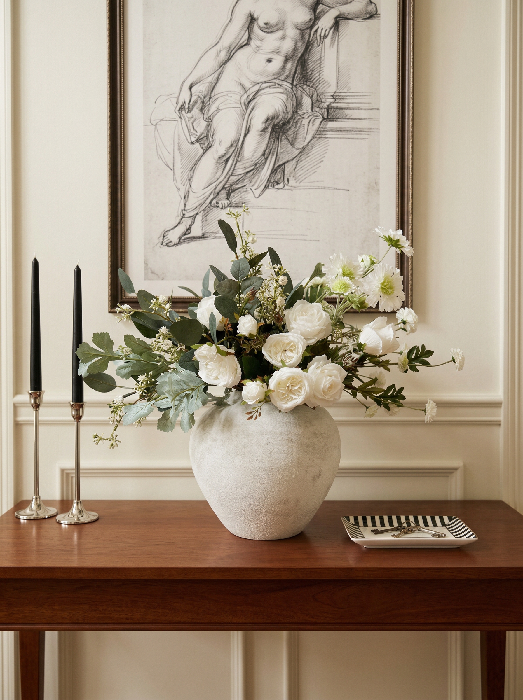 Floral arrangement in a vase on a wooden table with a classical painting in the background.