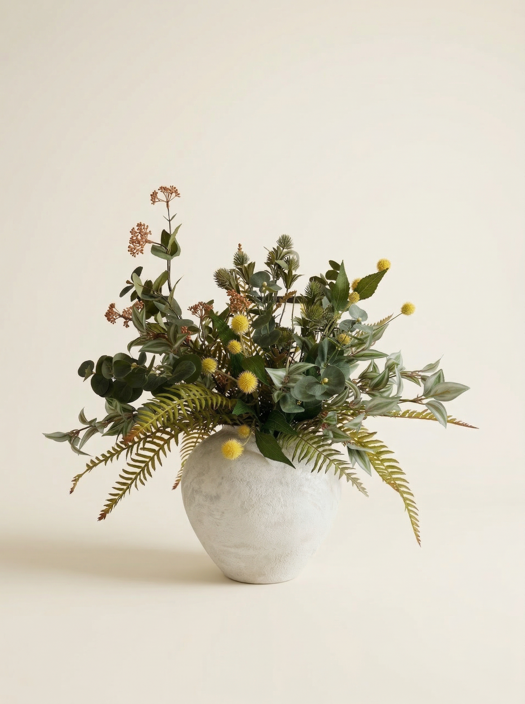 Vase with greenery and small yellow flowers on a light background