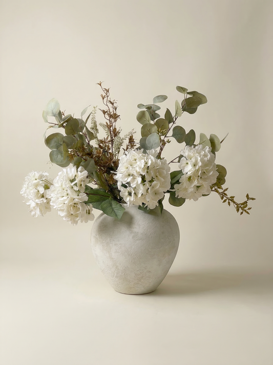 White flowers in a textured vase on a beige background